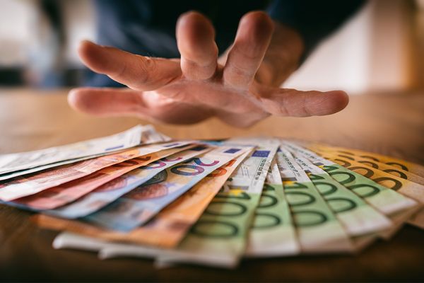 Foto: Hand über Geldscheinen